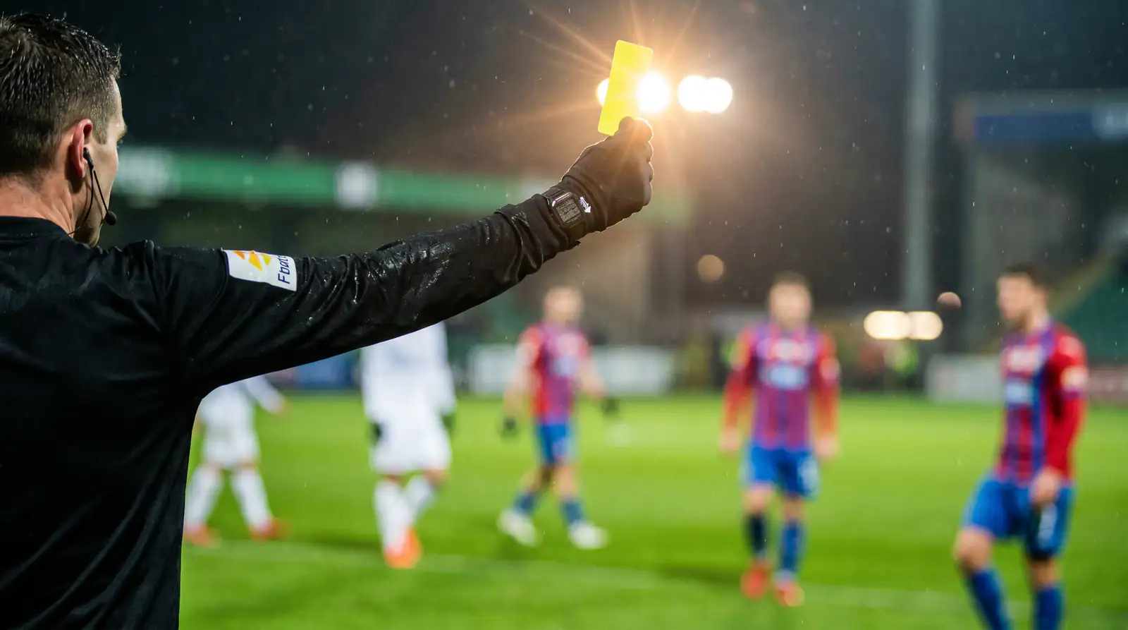 Football referee showing yellow card during Premier League match